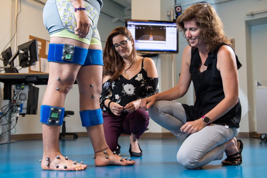 Deux professionnelles placent des marques sur la jambe d’une femme pour un projet de capture de mouvement.