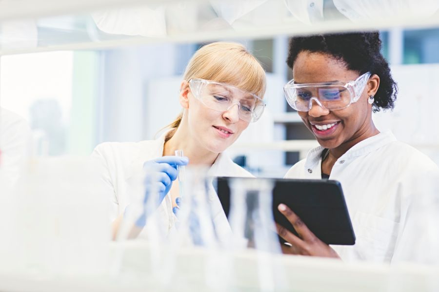 Une professeure de race blanche et une étudiante noire regardant un ordinateur portable dans un laboratoire.
