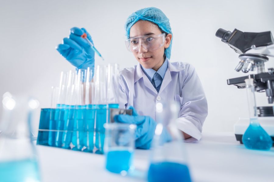 Un scientifique asiatique menant des recherches et mélangeant des produits chimiques à l’intérieur d’un laboratoire.