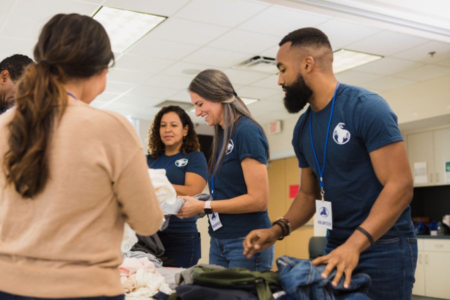 A diverse group of professionals working as volunteers and folding donated clothing.